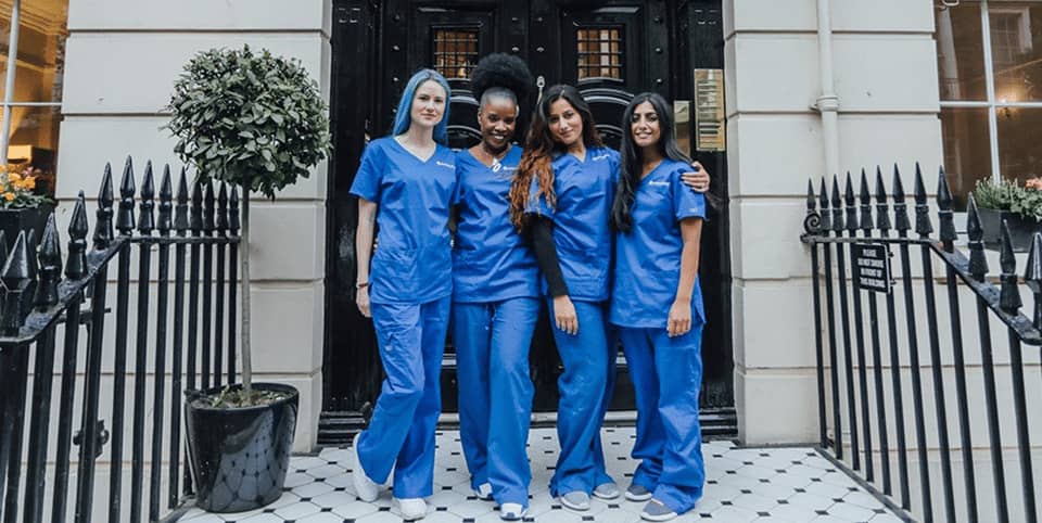 EMsculpt muscle building London - four nurses in blue scrubs outside a Georgian clinic Four nurses in blue scrubs outside a Georgian clinic entrance at our Harley Street clinic, EMsculpt muscle building London